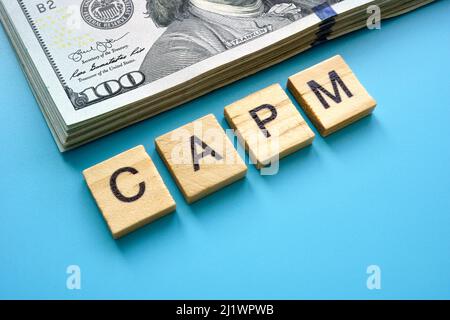 Letters CAPM Capital Asset Pricing Model and a bundle of money. Stock Photo