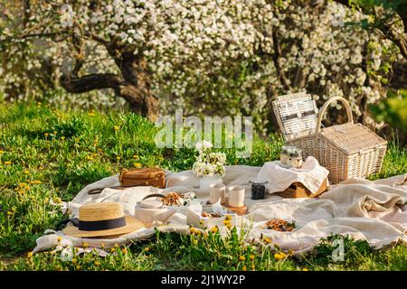 Breakfast picnic with waffles and tea in spring blossom garden on a white tablecloth on a sunny day, cherry blossoms. Outdoor, picnic, brunch, spring Stock Photo