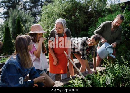 Happy farmers family working with garden tools outdoors at community farm. Stock Photo