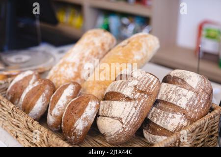 Close-up of fresh various baked breads in wicker basket at coffee shop. unaltered, food and small cafe business concept. Stock Photo