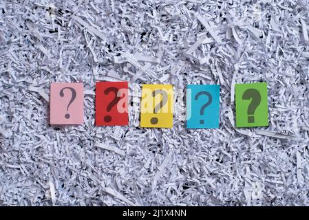 Colorful question mark symbol on paper against shredded paper background Stock Photo