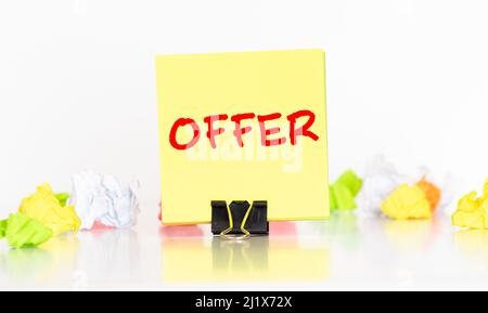 OFFER word written on a white sticker holding in a man's hand. Blurring man in suit. Stock Photo