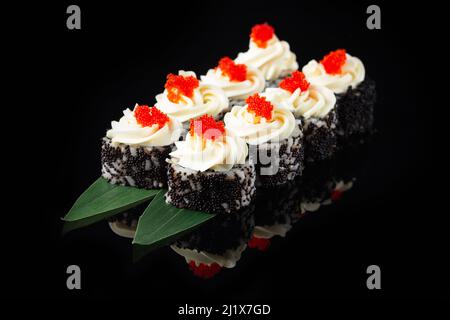 Traditional delicious fresh sushi roll set on a black background with reflection. Sushi roll with rice, nori, cream cheese, tobiko caviar, avocado. Su Stock Photo