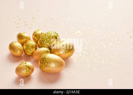 Easter eggs with gold sequins on a beige background.  Stock Photo