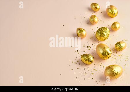 Easter eggs with gold sequins on a beige background.  Stock Photo