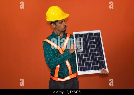 Solar worker in protective work clothes holding photovoltaic panel isolated. Concept of designing power plants. Stock Photo