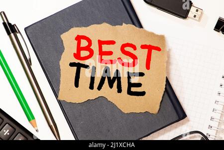 best TIME written in a notebook near a white alarm clock. Stock Photo