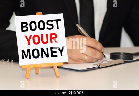 Handwriting text Boost Your Money. Concept meaning increase your bank saving using effective methods Paper clip and torn cardboard placed above a wood Stock Photo