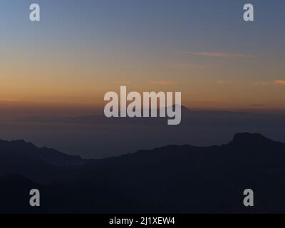 Beautiful view over the western mountains of Gran Canaria, Canary Islands, Spain after sunset with the silhouettes of Tenerife island and Mount Teide. Stock Photo