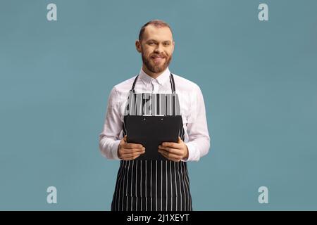 https://l450v.alamy.com/450v/2j1xeyt/waiter-wearing-an-apron-and-holding-a-menu-isolated-on-blue-background-2j1xeyt.jpg