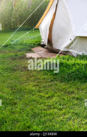An old style canvas bell tent at a camp site in a lush green field set up for posh camping also known as glamping. Stock Photo