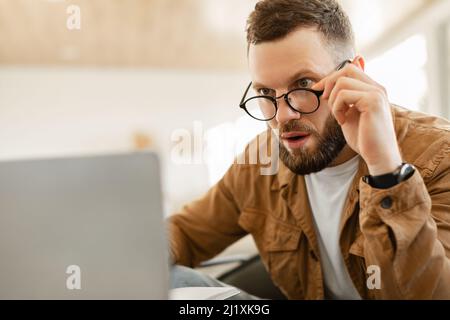 Man Looking At Laptop Screen In Shock Above Glasses Indoor Stock Photo