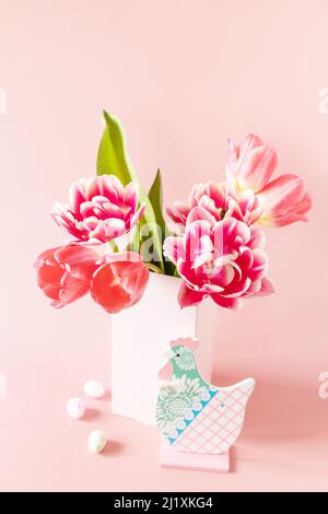 Bouquet of pink and purple tulips with colorful quail eggs over pink background. Spring and Easter holiday concept. Stock Photo