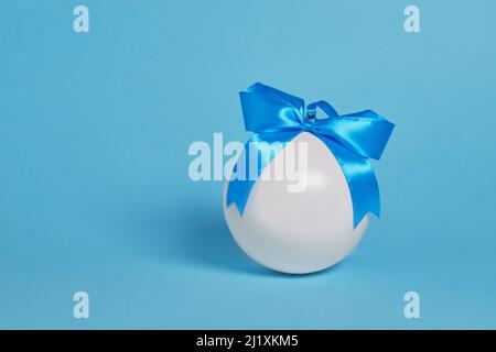 Christmas tree toy. A white ball with a blue bow on a blue background Stock Photo