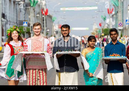 A group of people in national costumes of different nationalities and ethnicities look at the camera and smile. Stock Photo