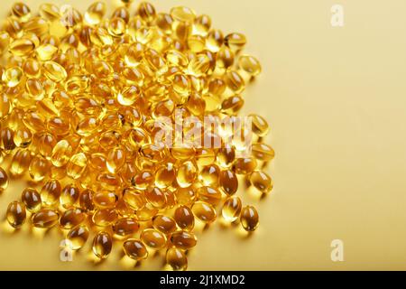 The texture of the capsules in the shell with liquid vitamin D3 in full screen. Gold capsules with a dietary supplement for joints teeth and bones. Stock Photo