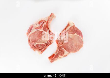 Two pieces of raw pork chops bone in isolated on white background. Top view. Stock Photo