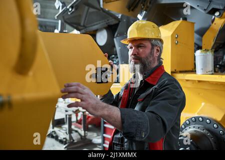Serious mature technician in uniform controlling the work of equipment in factory Stock Photo