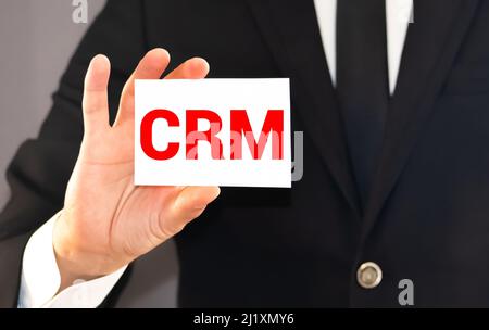 CRM letters or Customer Relationship Management on the card shown by a businessman. Stock Photo