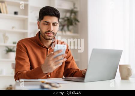Portrait of man using smartphone and pc at home Stock Photo