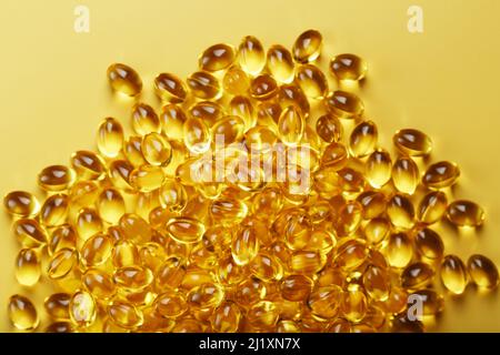 The texture of the capsules in the shell with liquid vitamin D3 in full screen. Gold capsules with a dietary supplement for joints teeth and bones. Stock Photo