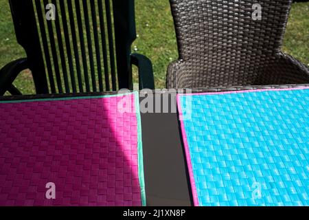 A  green plastic table and chairs laid out with place mats in a garden ready for a summer Barbeque and meal. Stock Photo
