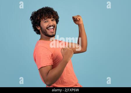 Positive indian guy having good day, raising hands up Stock Photo