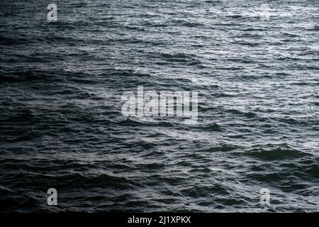 Sunlight relecting off the sea with  bright refelected highlights on the textured surface. Stock Photo