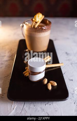 coffee with chocolate paste and cookies on black dishes on a black plate Stock Photo