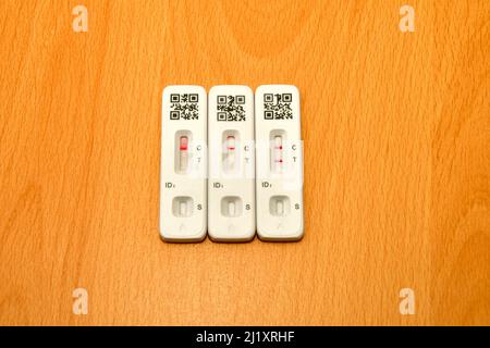 Two negative lateral flow tests with a positive test on the right, all with unidentifiable QR codes. No people. Stock Photo