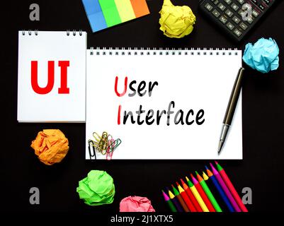 UI user interface symbol. Concept words UI user interface on white note. Metallic pen, calculator, pencil. Beautiful black background. Copy space. Bus Stock Photo