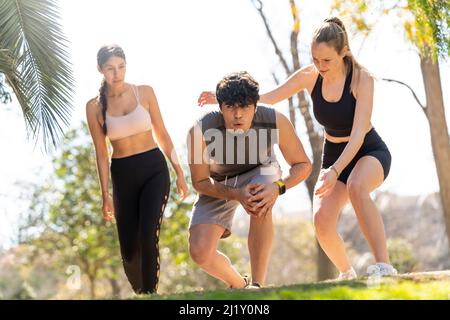 Two women help a man with an injured knee in the park Stock Photo