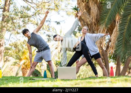 Three young people doing sports with a laptop and in the park Stock Photo