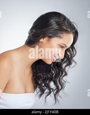Curly hair it is. Shot of an attractive young woman standing alone and posing with curly hair in the studio. Stock Photo