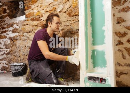 Young man working on plastering drywall at home renovation Stock Photo