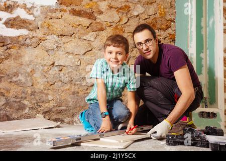 Father with son measure and cut plasterboard doing renovation