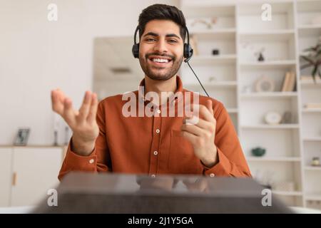 Arab man using laptop wearing headset sitting at desk Stock Photo