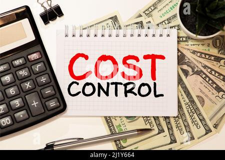 COST CONTROL. Black notebook and computer keyboard on a white office desk. Stock Photo
