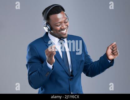 Dont forget to take a few moments for yourself. Cropped shot of a handsome young businessman using his headphones to listen to music in studio against Stock Photo