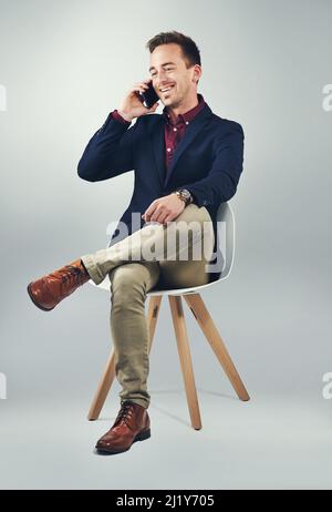 The man to call to make it happen. Studio shot of a confident young businessman using a mobile phone against a gray background. Stock Photo