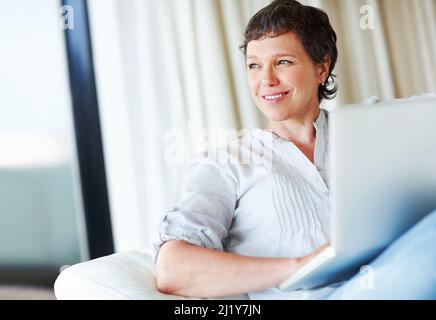 Thoughtful business woman with laptop. Thoughtful mature business woman sitting on couch using laptop. Stock Photo