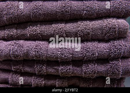 Textured violet bath towels stacked close up. Stock Photo