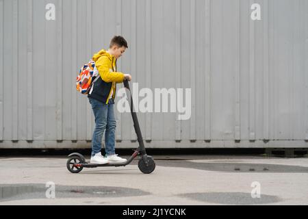 Teenager with a backpack rides on electric scooter Stock Photo
