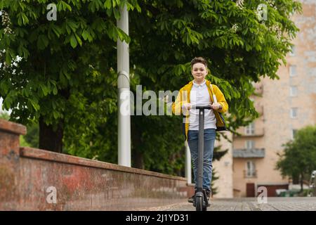 Joyful teenager rides on electric scooter outdoor Stock Photo
