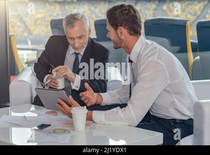 Portrait of business partners discussing important papers sitting at office Stock Photo