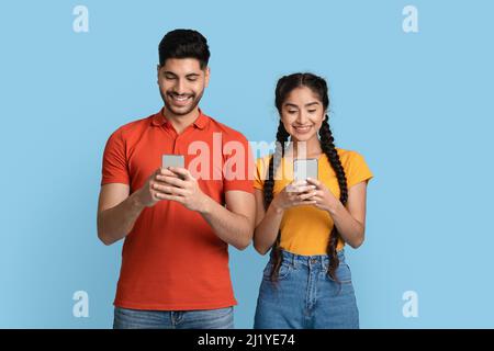 Online Communication. Portrait Of Happy Middle Eastern Couple Using Smartphones Stock Photo
