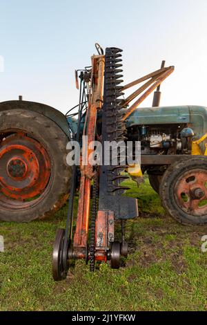 An old antique hedge trimmer mounted on a vintage tractor Stock Photo