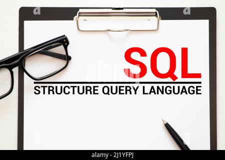 Top view of keyboard,trash paper,clipboard,pen and paper written with SQL Stock Photo