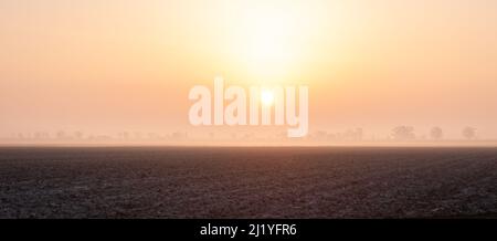 Panorama of the sun rising over a misty landscape in the western part of The Netherlands Stock Photo