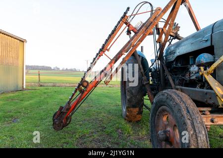 An old antique hedge trimmer mounted on a vintage tractor Stock Photo